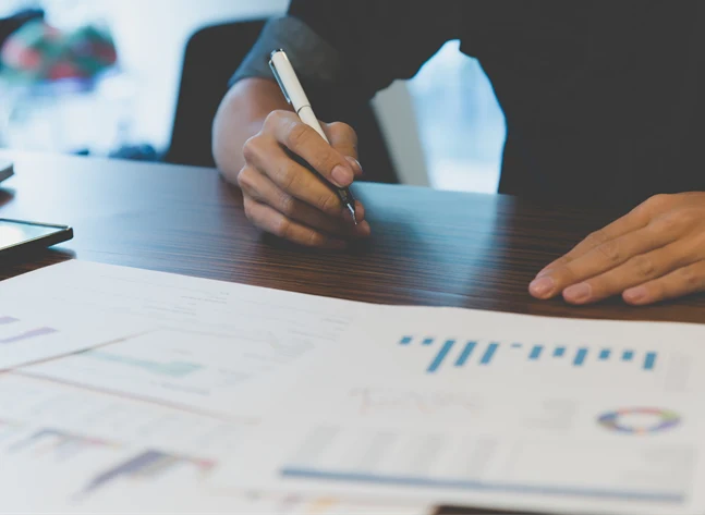 Bild på person med utskrivna papper framför sig med olika typer av grafer och diagram.