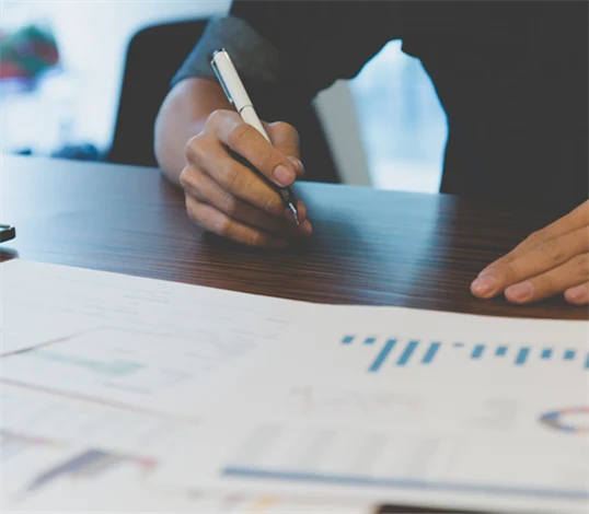 Bild på person med utskrivna papper framför sig med olika typer av grafer och diagram.