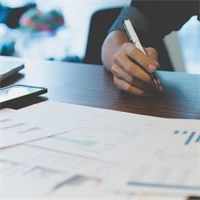 Bild på person med utskrivna papper framför sig med olika typer av grafer och diagram.